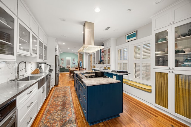 kitchen featuring blue cabinetry, light wood-type flooring, a sink, white cabinets, and stainless steel appliances