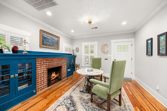 interior space with visible vents, ornamental molding, wood finished floors, and a fireplace