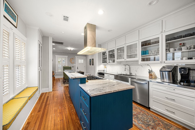 kitchen with appliances with stainless steel finishes, a sink, a center island, island range hood, and blue cabinets