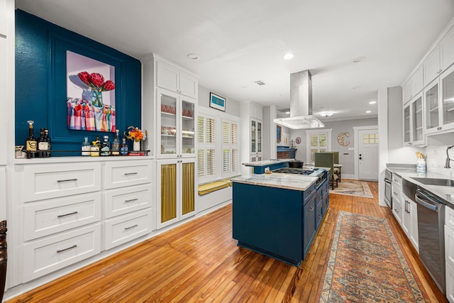 kitchen with a kitchen island, island exhaust hood, a sink, light wood finished floors, and white cabinetry