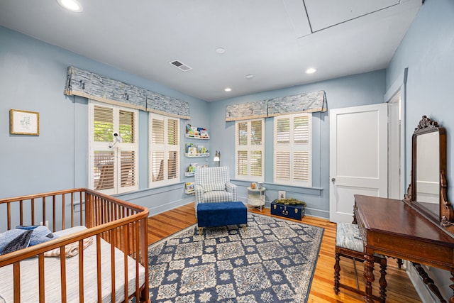 bedroom with baseboards, recessed lighting, wood finished floors, and visible vents
