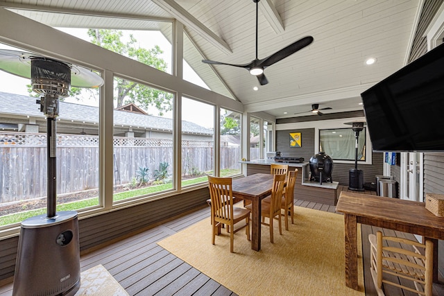 sunroom with recessed lighting, a wood stove, lofted ceiling with beams, and a deck