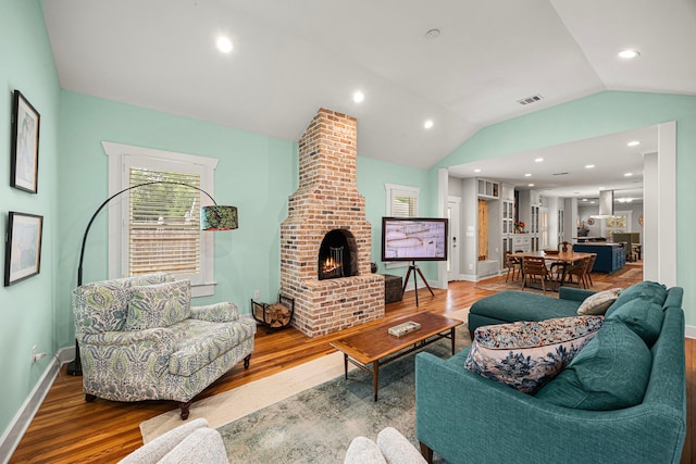 living room with lofted ceiling, wood finished floors, and a fireplace