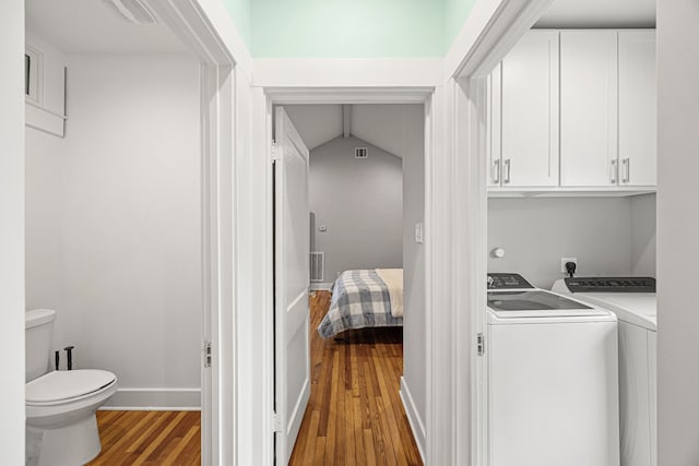 laundry area with visible vents, wood finished floors, baseboards, washing machine and clothes dryer, and cabinet space