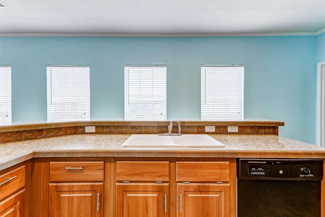 kitchen featuring light countertops, brown cabinets, a sink, and dishwasher