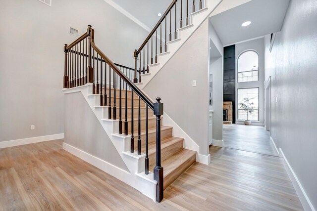 stairs featuring baseboards, a high ceiling, and wood finished floors