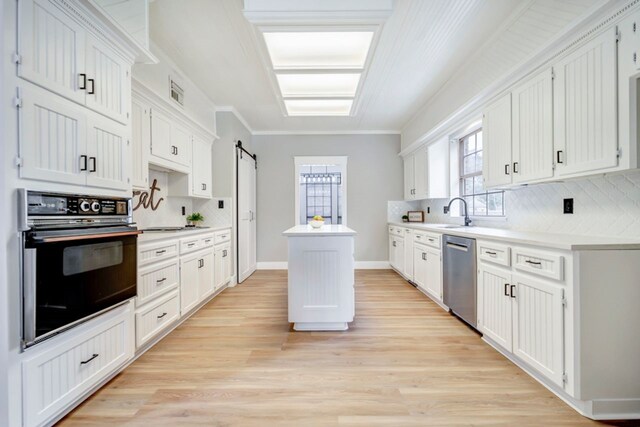 kitchen with a kitchen island, backsplash, dishwasher, light countertops, and black oven