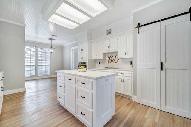 kitchen with light wood-style floors, a barn door, wall oven, and white cabinetry