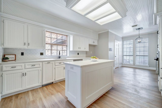 kitchen featuring decorative backsplash, a center island, white cabinetry, a sink, and light wood-style flooring