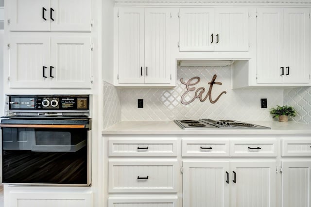 kitchen featuring electric cooktop, oven, light countertops, white cabinetry, and tasteful backsplash