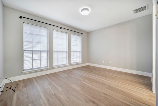spare room featuring baseboards, light wood-type flooring, and visible vents