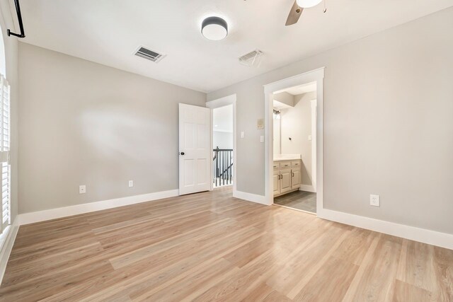 unfurnished bedroom with visible vents, light wood finished floors, ensuite bath, and baseboards