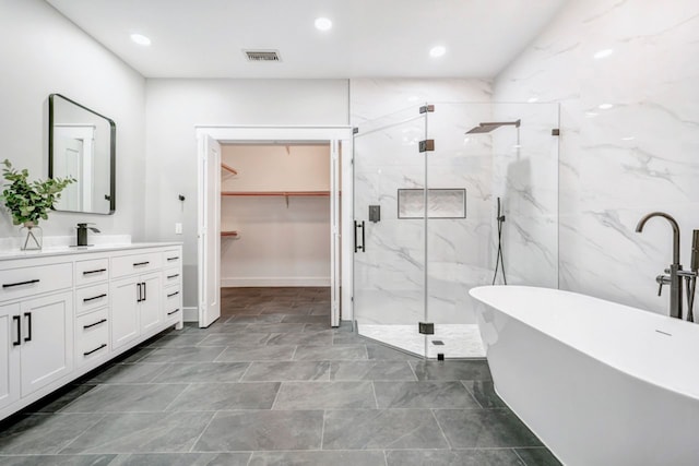 full bath featuring visible vents, vanity, a walk in closet, a soaking tub, and a marble finish shower
