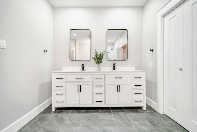 bathroom with double vanity, baseboards, a sink, and marble finish floor