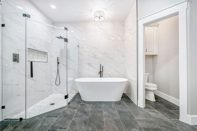 bathroom featuring a freestanding bath, tile walls, toilet, marble finish floor, and a marble finish shower