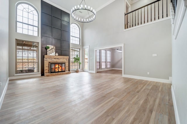 unfurnished living room featuring baseboards, ornamental molding, wood finished floors, and a towering ceiling