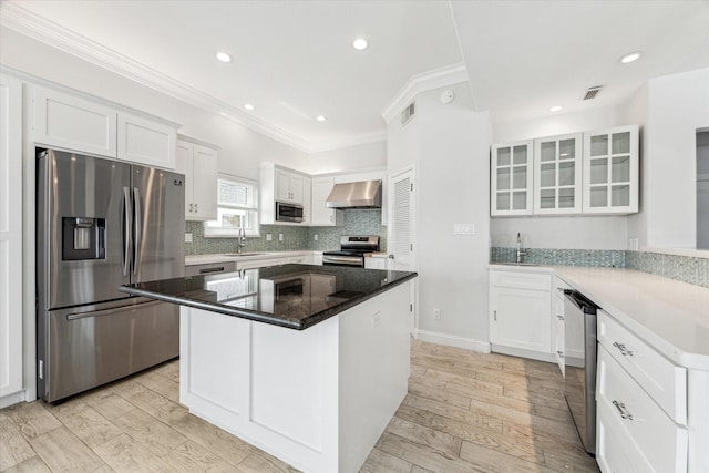 138 Isles End Rd, Tiki Island, TX 77554 - kitchen with appliances with stainless steel finishes, a sink, wall chimney exhaust hood, ornamental molding, and white cabinetry