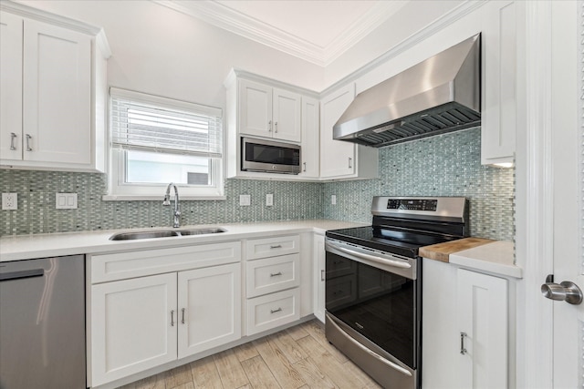 138 Isles End Rd, Tiki Island, TX 77554 - kitchen featuring wall chimney exhaust hood, appliances with stainless steel finishes, a sink, crown molding, and light countertops