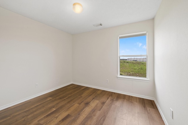 empty room featuring visible vents, baseboards, and wood finished floors
