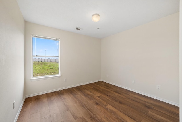 spare room featuring baseboards, hardwood / wood-style floors, and visible vents