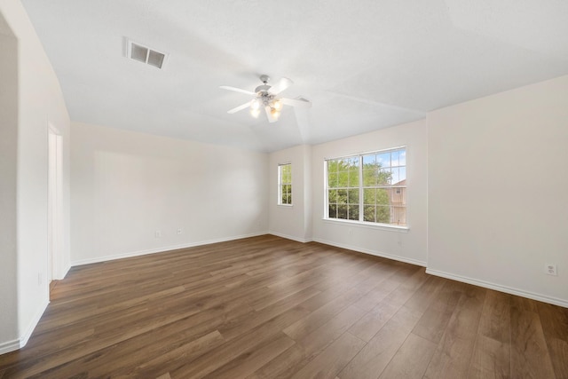 spare room featuring baseboards, a ceiling fan, dark wood-style flooring, and visible vents