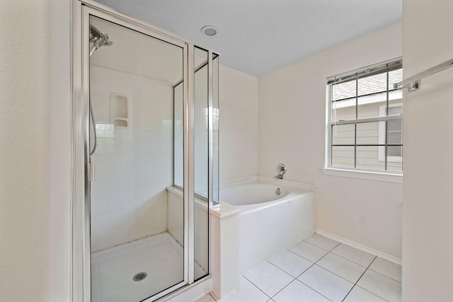 bathroom with baseboards, tile patterned flooring, a shower stall, and a bath