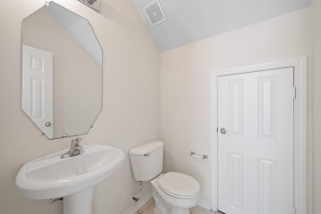 bathroom with visible vents, a sink, baseboards, toilet, and lofted ceiling