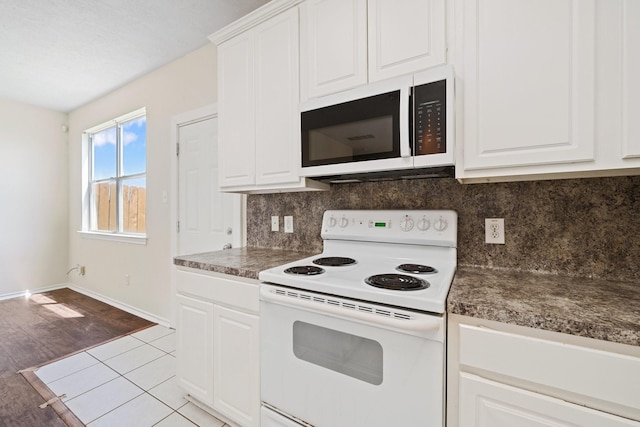 kitchen with baseboards, tasteful backsplash, white appliances, and white cabinetry