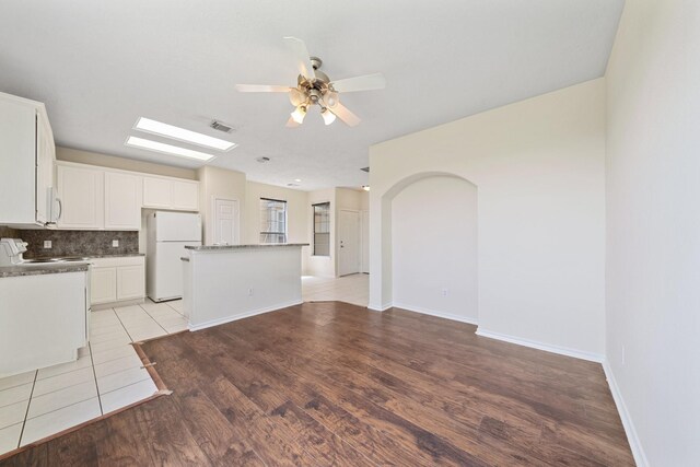 kitchen featuring light wood finished floors, white appliances, a ceiling fan, backsplash, and a kitchen island