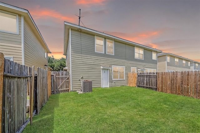 back of property with a lawn, a fenced backyard, and central AC