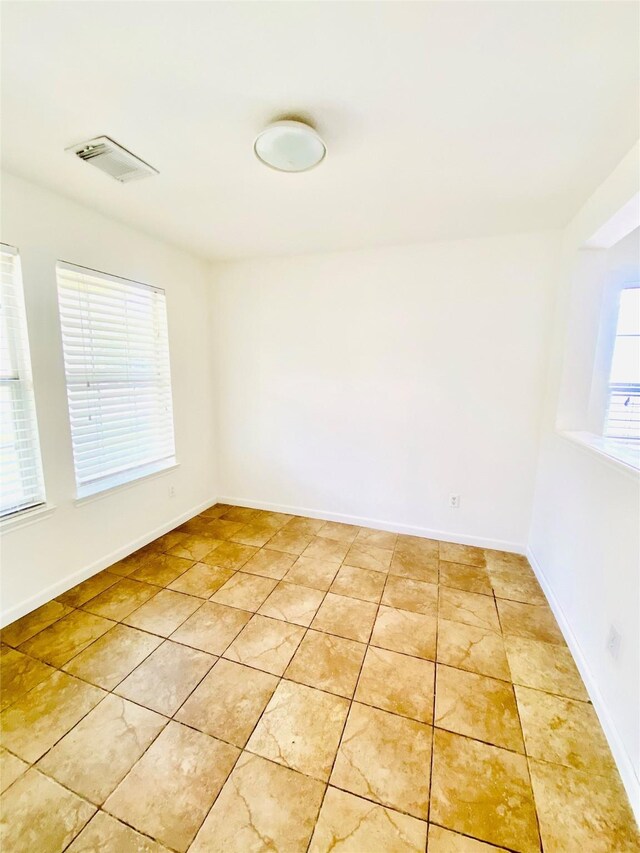 unfurnished room featuring light tile patterned flooring, baseboards, and visible vents