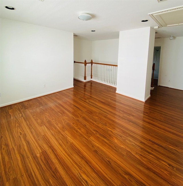 spare room featuring baseboards, attic access, and wood finished floors