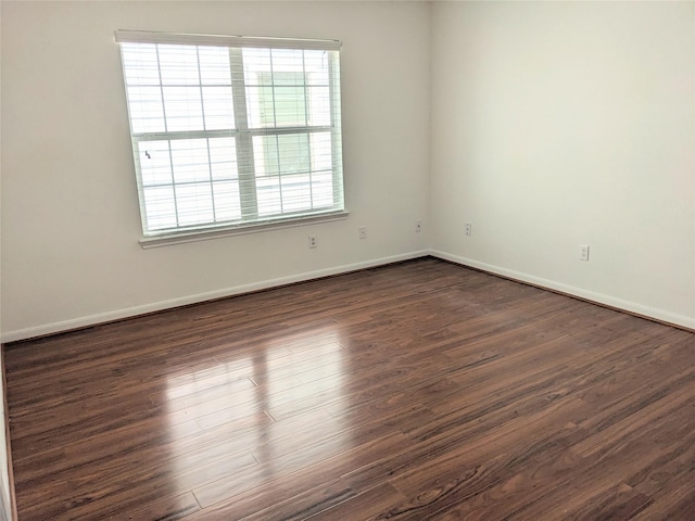 spare room featuring baseboards and dark wood-type flooring