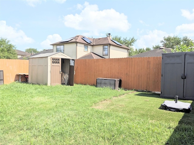 view of yard featuring a fenced backyard, a storage unit, and an outbuilding