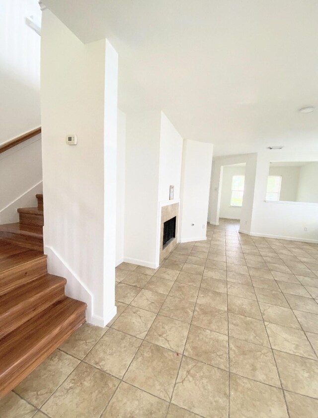 interior space with baseboards, light tile patterned floors, stairway, and a fireplace