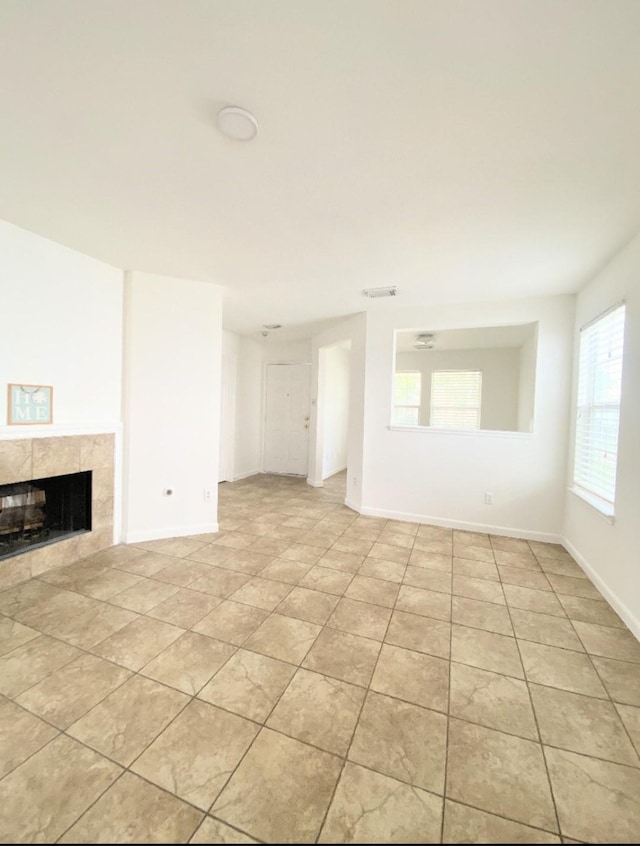 unfurnished living room with baseboards, light tile patterned flooring, and a fireplace