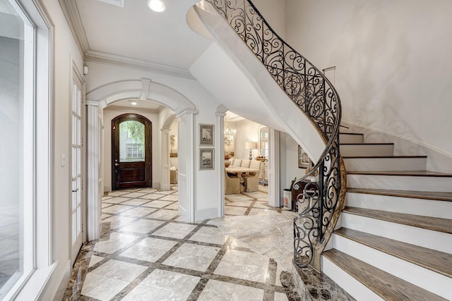 foyer entrance with arched walkways, stairs, ornate columns, ornamental molding, and recessed lighting