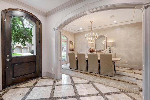 entrance foyer with crown molding, an inviting chandelier, arched walkways, baseboards, and ornate columns