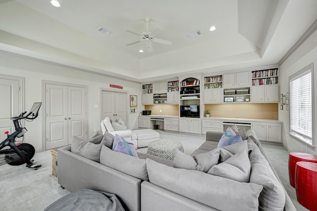 living area featuring a tray ceiling, light colored carpet, and visible vents