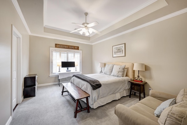 carpeted bedroom with a tray ceiling, ornamental molding, and ceiling fan