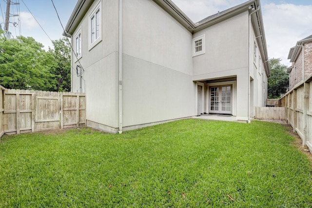 rear view of property with french doors, stucco siding, a lawn, and a fenced backyard