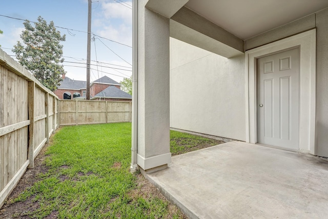 entrance to property featuring stucco siding, a patio area, fence, and a yard