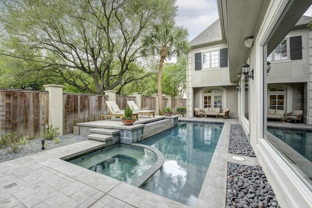 view of pool featuring a fenced backyard, a pool with connected hot tub, a patio area, and outdoor lounge area