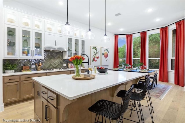 16427 Cat Ct, Conroe, TX 77302 - kitchen with light countertops, tasteful backsplash, stainless steel gas cooktop, and a center island with sink