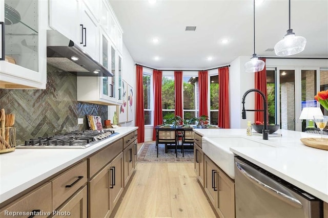 16427 Cat Ct, Conroe, TX 77302 - kitchen with hanging light fixtures, light wood-type flooring, light countertops, under cabinet range hood, and stainless steel appliances