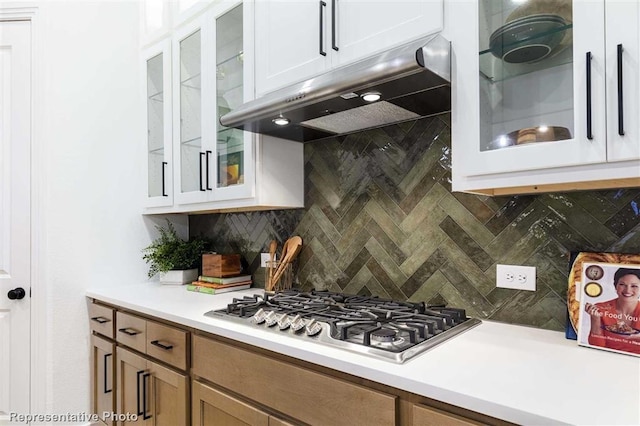 16427 Cat Ct, Conroe, TX 77302 - kitchen with glass insert cabinets, backsplash, light countertops, stainless steel gas stovetop, and under cabinet range hood