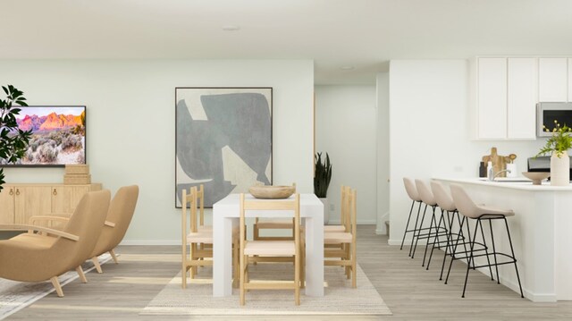 dining space featuring baseboards and light wood-style flooring