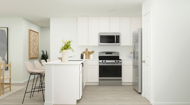kitchen with a peninsula, a breakfast bar, light wood-style floors, white cabinets, and stainless steel appliances