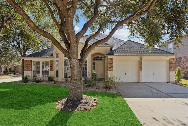 view of front of home featuring roof with shingles, a front yard, a garage, brick siding, and concrete driveway