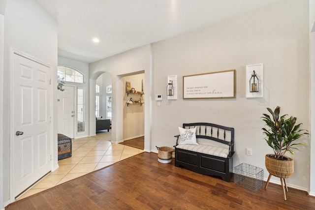 foyer entrance featuring arched walkways, baseboards, recessed lighting, and wood finished floors
